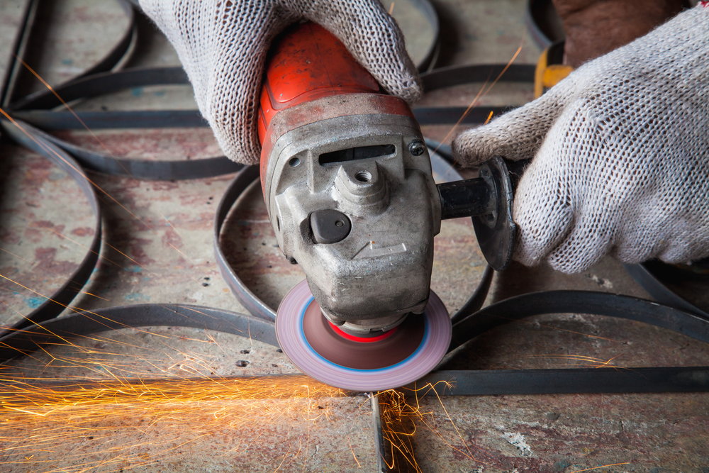 worker grinding steel using angle grinder