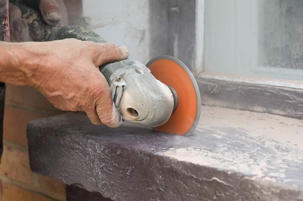 man cutting concrete using angle grinder