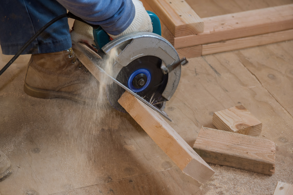 carpenter using circular saw to cut scant timber
