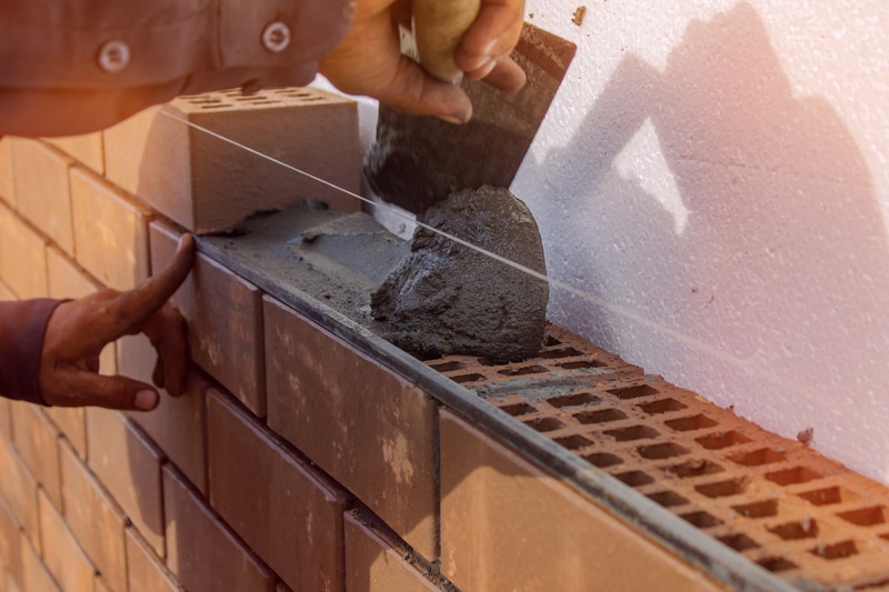 worker laying mortar on a brick